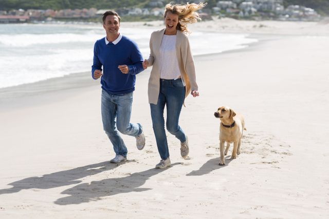 Mature couple walking on the beach with their dog - Download Free Stock Photos Pikwizard.com