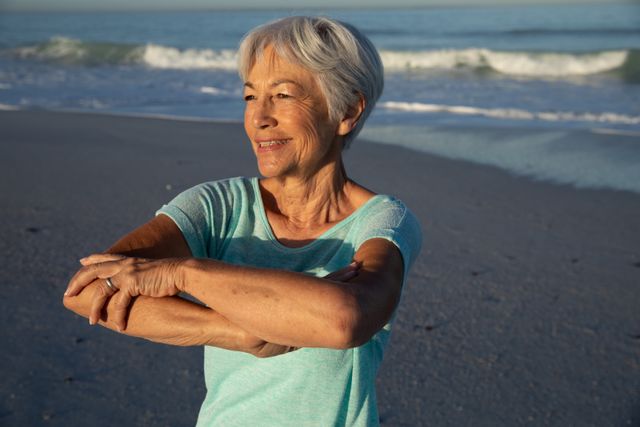 Senior woman performing stretching exercise on the beach - Download Free Stock Photos Pikwizard.com