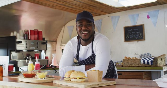 Portrait of african american man wearing apron smiling while standing in the food truck. food truck and street food concept