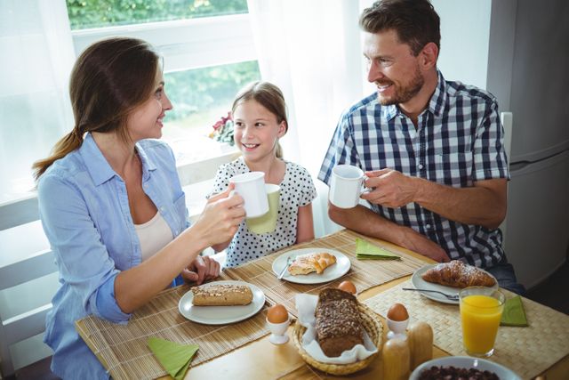 Family toasting a cup of coffee while having breakfast - Download Free Stock Photos Pikwizard.com