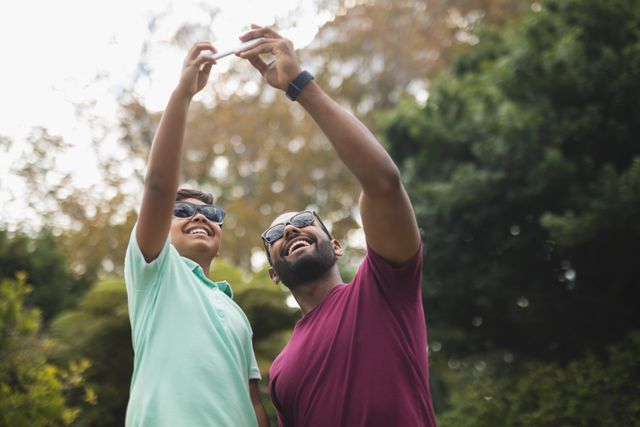Cheerful father taking selfie with son at park - Download Free Stock Photos Pikwizard.com