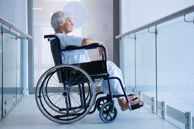 Disabled senior patient on wheelchair in hospital passageway - Download Free Stock Photos Pikwizard.com