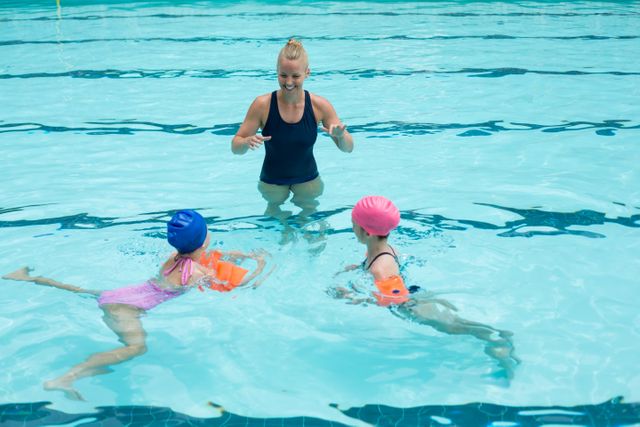 Happy instructor assisting children in swimming pool - Download Free Stock Photos Pikwizard.com