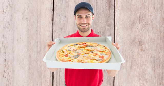 Delivery man showing pizza against wall - Download Free Stock Photos Pikwizard.com