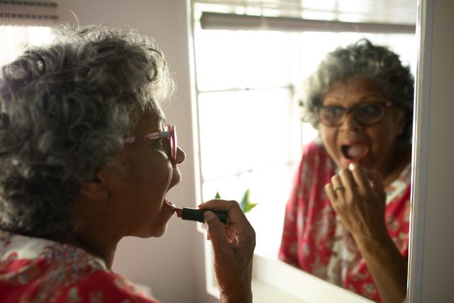 Senior woman applying lipstick while looking in the mirror - Download Free Stock Photos Pikwizard.com