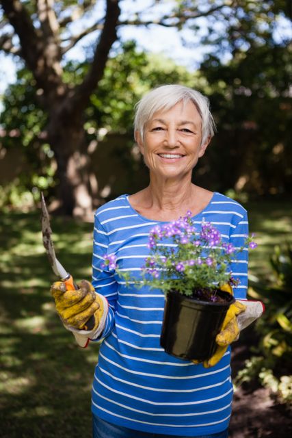 Portrait of smiling senior woman holding potted plant and trowel - Download Free Stock Photos Pikwizard.com