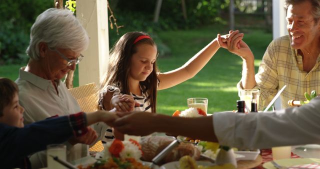 Happy caucasian family holding hands and praying before dinner in sunny garden - Download Free Stock Photos Pikwizard.com