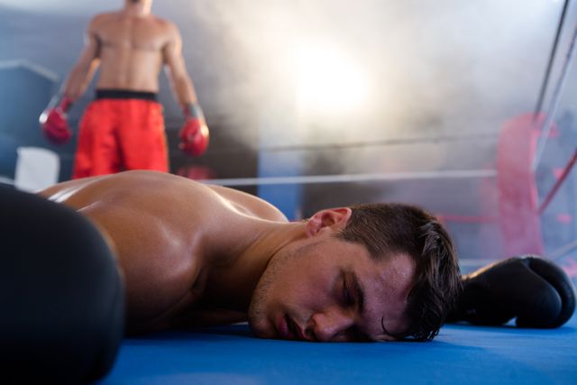 Unconscious male boxer lying by athlete in ring - Download Free Stock Photos Pikwizard.com