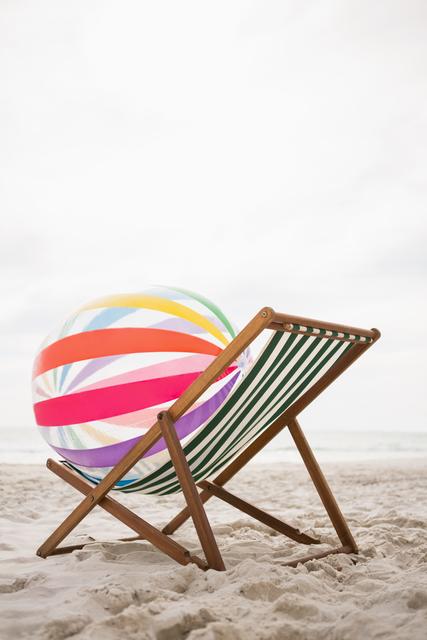 Striped beach ball kept on empty beach chair - Download Free Stock Photos Pikwizard.com
