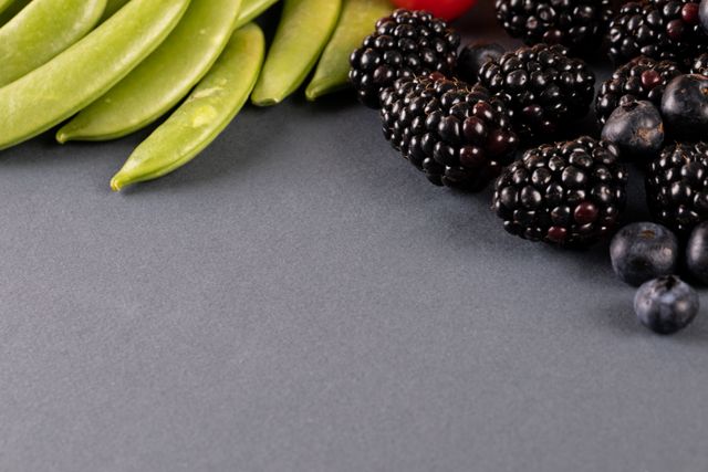 High angle close-up view of fresh berry fruits and green peas on gray background - Download Free Stock Photos Pikwizard.com