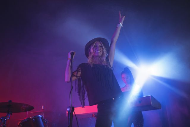 Female singer singing while musician playing piano in illuminated nightclub - Download Free Stock Photos Pikwizard.com