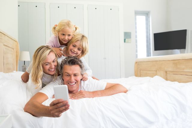 Happy family taking a selfie on mobile phone in the bed room - Download Free Stock Photos Pikwizard.com