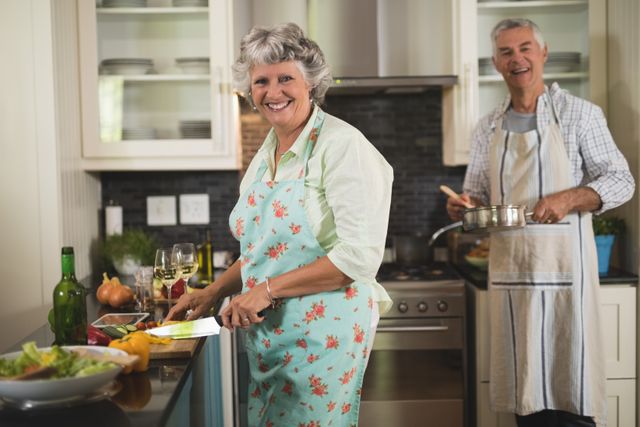 Smiling senior couple cooking in kitchen at home - Download Free Stock Photos Pikwizard.com