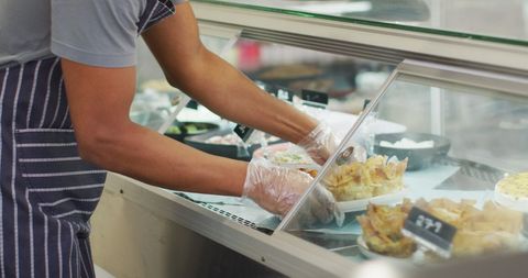 Image of midsection of biracial waiter taking food from fridge. coffee and bistro shop, running small independent business.