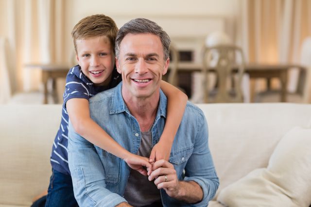 Smiling son embracing a father in living room - Download Free Stock Photos Pikwizard.com