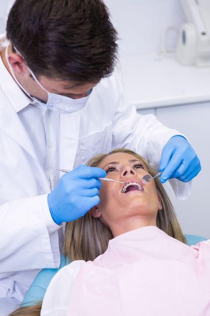 Close up of dentist holding equipment while examining woman - Download Free Stock Photos Pikwizard.com