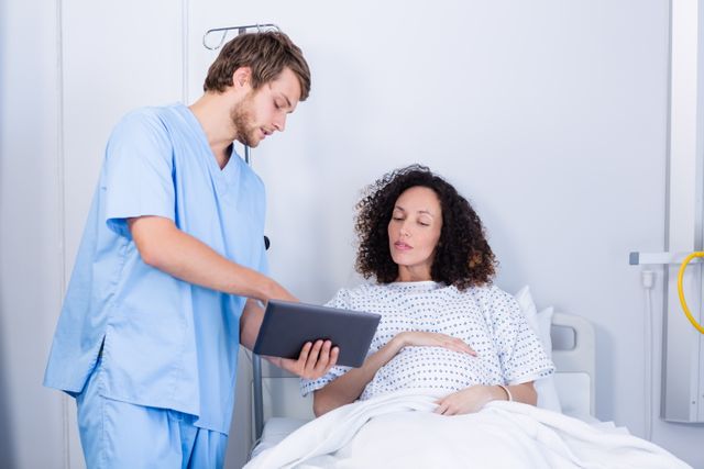 Doctor assisting pregnant woman on digital tablet in ward - Download Free Stock Photos Pikwizard.com