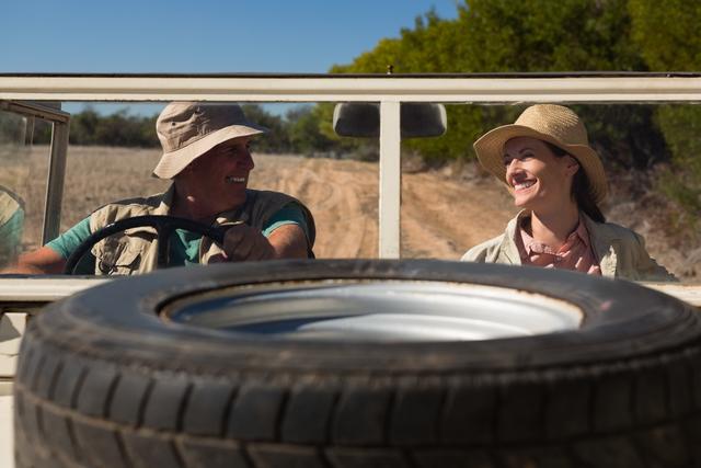 Tire on hood with smiling couple sitting in off road vehicle - Download Free Stock Photos Pikwizard.com
