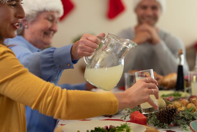 Caucasian old woman pouring a drink for the woman beside her at a christmas dinner table - Download Free Stock Photos Pikwizard.com