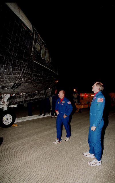 After landing at the Shuttle Landing Facility, STS-103 Pilot Scott J. Kelly (left) and Commander Curtis L. Brown Jr. (right) look at the tiles on orbiter Discovery. They and other crew members Mission Specialists Steven L. Smith, C. Michael Foale (Ph.D.), John M. Grunsfeld (Ph.D.), Jean-Francois Clervoy of France and Claude Nicollier of Switzerland, completed a successful eight-day mission to service the Hubble Space Telescope, spending the Christmas holiday in space in order to accomplish their mission before the end of 1999. During the mission, Discovery's four space-walking astronauts, Smith, Foale, Grunsfeld and Nicollier, spent 24 hours and 33 minutes upgrading and refurbishing Hubble, making it more capable than ever to renew its observations of the universe. Mission objectives included replacing gyroscopes and an old computer, installing another solid state recorder, and replacing damaged insulation in the telescope. Hubble was released from the end of Discovery's robot arm on Christmas Day. Main gear touchdown was at 7:00:47 p.m. EST. Nose gear touchdown occurred at 7:00:58 p.m. EST and wheel stop at 7:01:34 p.m. EST. This was the 96th flight in the Space Shuttle program and the 27th for the orbiter Discovery. The landing was the 20th consecutive Shuttle landing in Florida and the 13th night landing in Shuttle program history