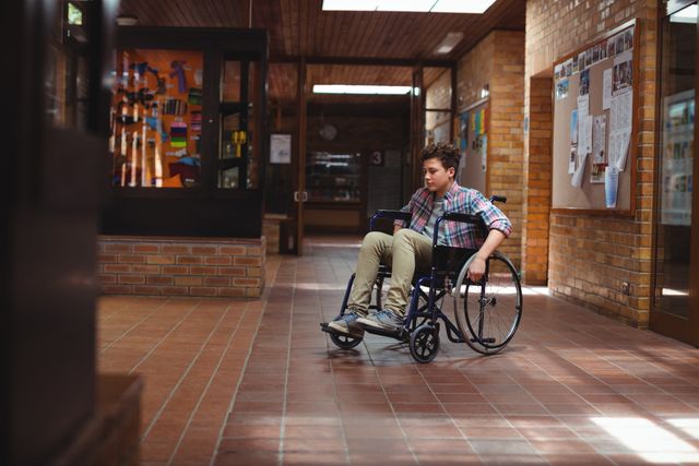 Disabled schoolboy on wheelchair in corridor at school - Download Free Stock Photos Pikwizard.com
