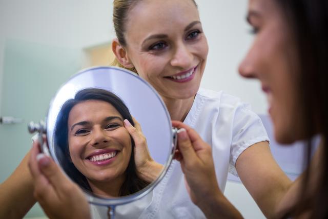 Woman checking her skin in the mirror after receiving cosmetic treatment - Download Free Stock Photos Pikwizard.com