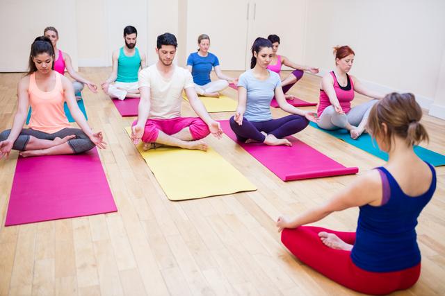 Group of people and trainer sitting in lotus position - Download Free Stock Photos Pikwizard.com