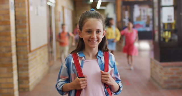 Portrait of happy caucasian schoolgirl standing in corridor looking at camera. children in primary school.