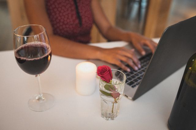 Midsection of mixed race woman writing on laptop and having red wine - Download Free Stock Photos Pikwizard.com