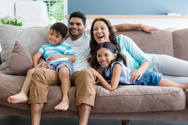 Happy parents and kids sitting on sofa in living room - Download Free Stock Photos Pikwizard.com