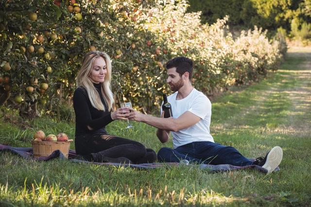 Couple having wine in apple orchard - Download Free Stock Photos Pikwizard.com