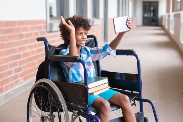 Smiling african american elementary schoolboy waving hand during video call over digital tablet. unaltered, education, disability, wireless technology, physical disability and school concept.