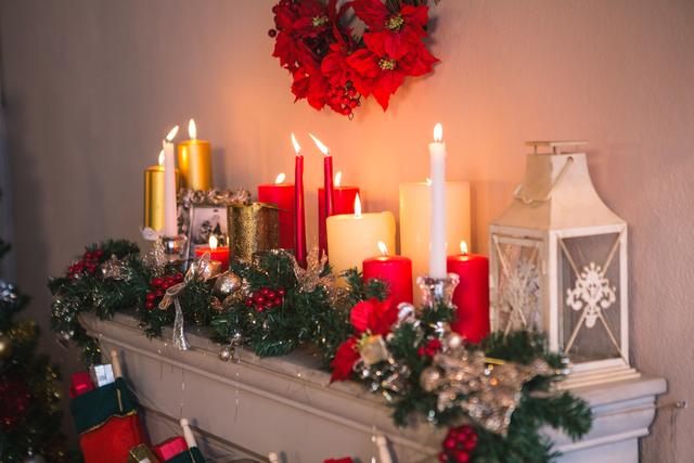 Candles and christmas decorations arranged on fireplace at home