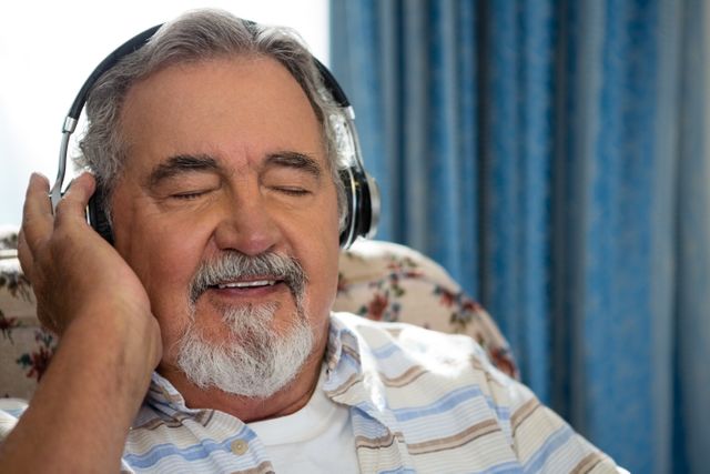 Close up of senior man listening music through headphones in nursing home