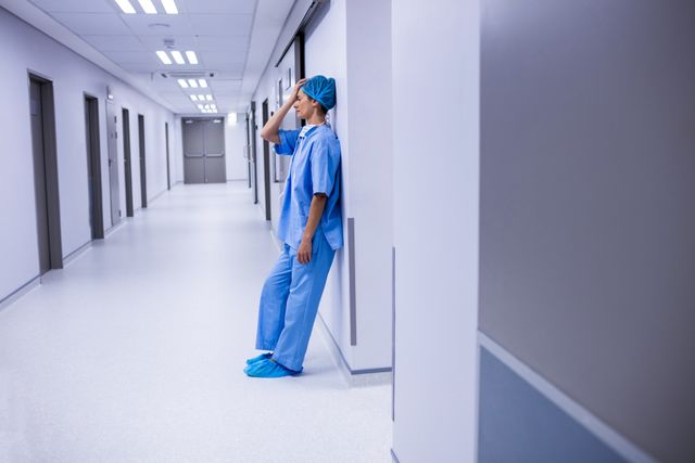 Sad surgeon leaning on wall in corridor - Download Free Stock Photos Pikwizard.com