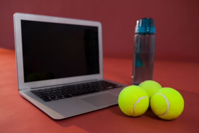 Close up of tennis balls by laptop and water bottle - Download Free Stock Photos Pikwizard.com