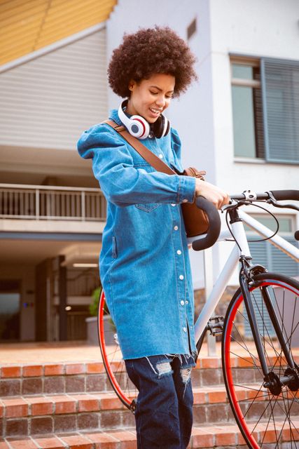 Mixed race female business creative wearing headphone arriving with bike outside workplace - Download Free Stock Photos Pikwizard.com