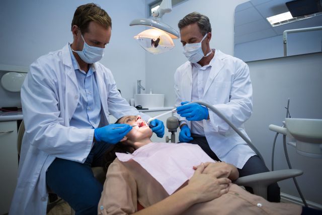 Dentists examining a female patient with tools - Download Free Stock Photos Pikwizard.com