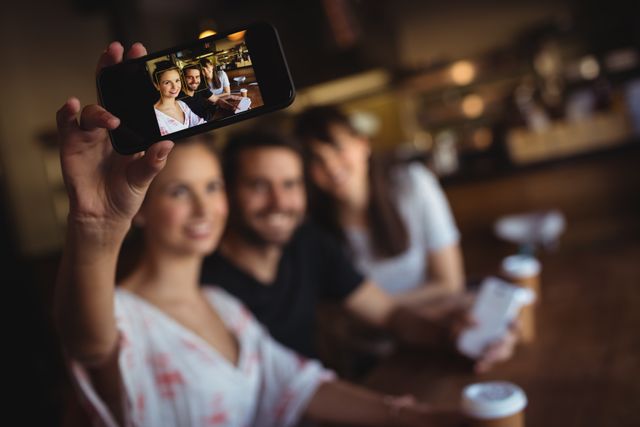 Friends taking a selfie on mobile phone at restaurant