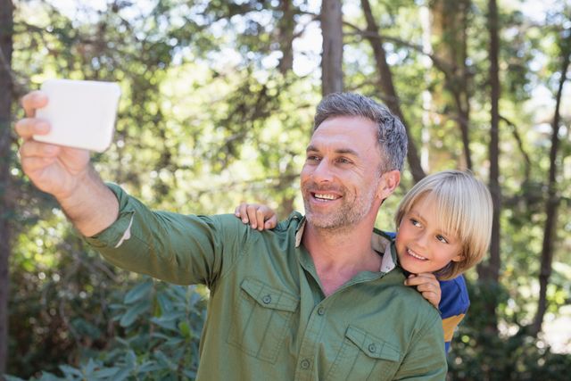 Smiling father and son taking selfie in forest - Download Free Stock Photos Pikwizard.com