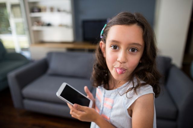 Girl sticking out tongue while holding mobile phone - Download Free Stock Photos Pikwizard.com