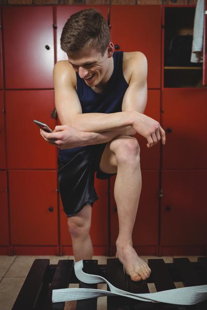 Sportsman using mobile phone in locker room