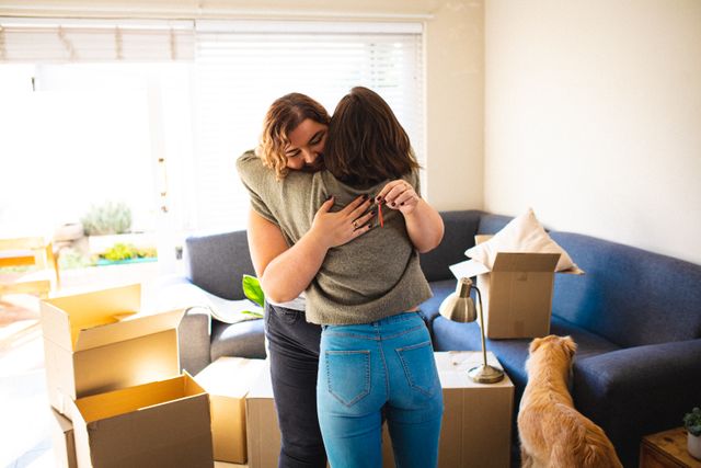Lesbian couple hugging in living room during moving in. domestic lifestyle, spending free time at home.