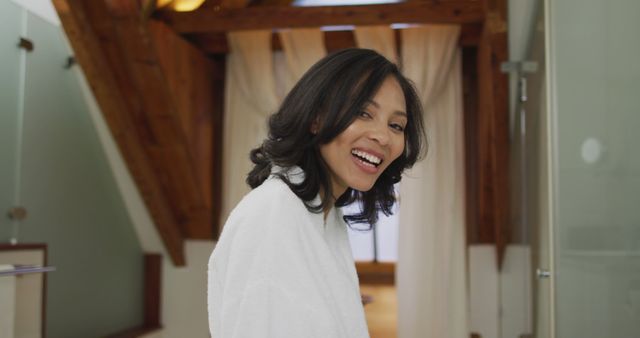 Portrait of mixed race woman wearing bathrobe looking at camera and smiling. domestic life, spending quality free time relaxing at home.