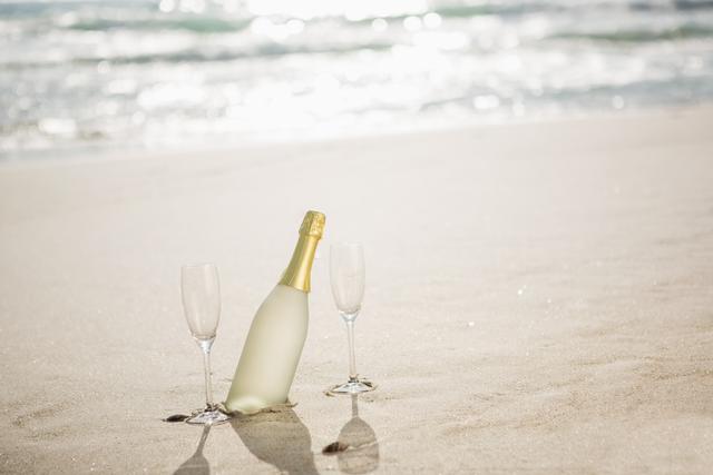 Champagne bottle and two glasses on sand - Download Free Stock Photos Pikwizard.com