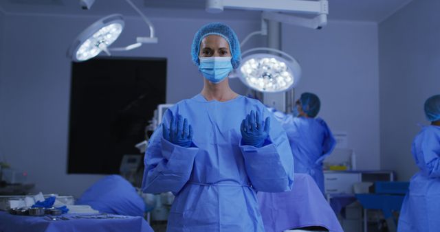 Portrait of caucasian female surgeon wearing face mask and protective clothing in operating theatre. medicine, health and healthcare services during covid 19 coronavirus pandemic.
