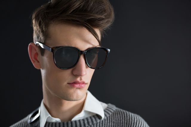 Androgynous man in sunglasses posing against black background - Download Free Stock Photos Pikwizard.com