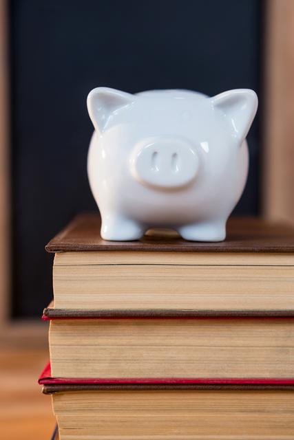 Close-up of books stack with a piggy bank - Download Free Stock Photos Pikwizard.com