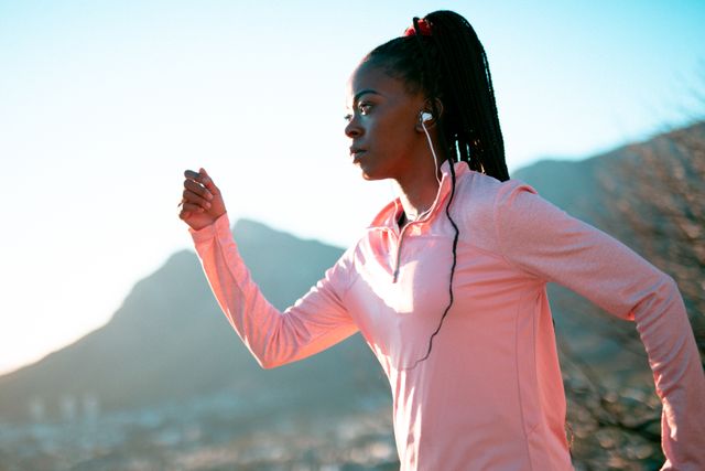 Fit african american woman exercising in countryside, wearing wireless earphones - Download Free Stock Photos Pikwizard.com