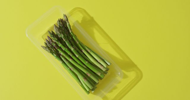 Image of bundle of fresh asparagus in plastic container with copy space over green background - Download Free Stock Photos Pikwizard.com